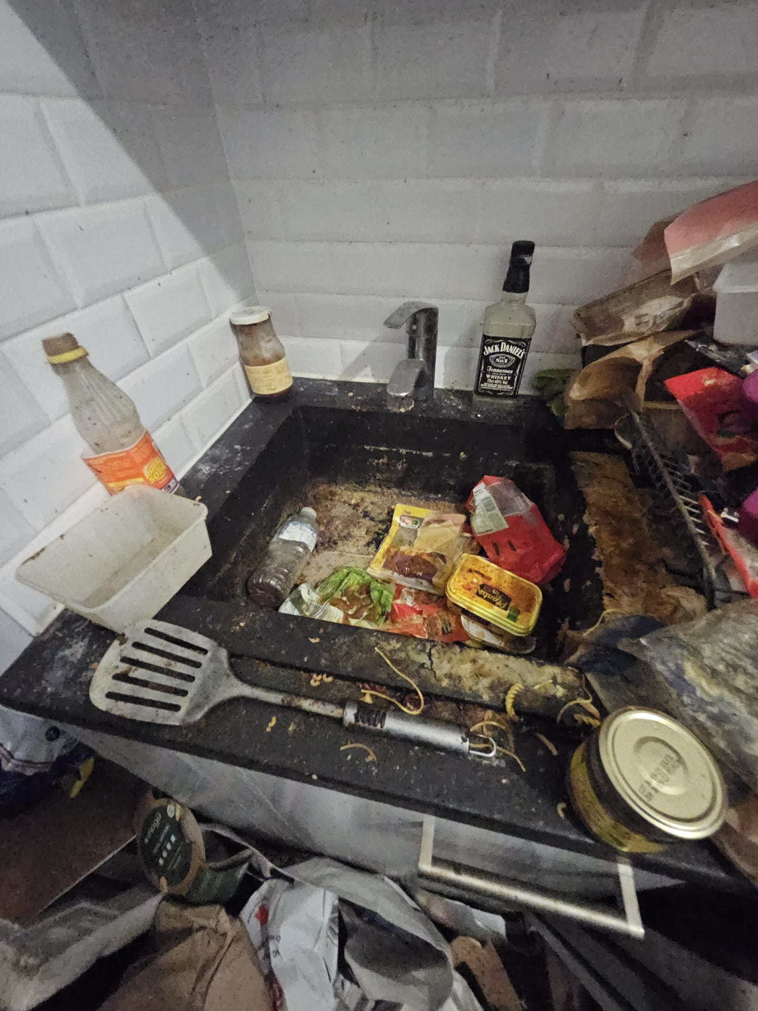 Évier rempli de vaisselle et déchets à évacuer