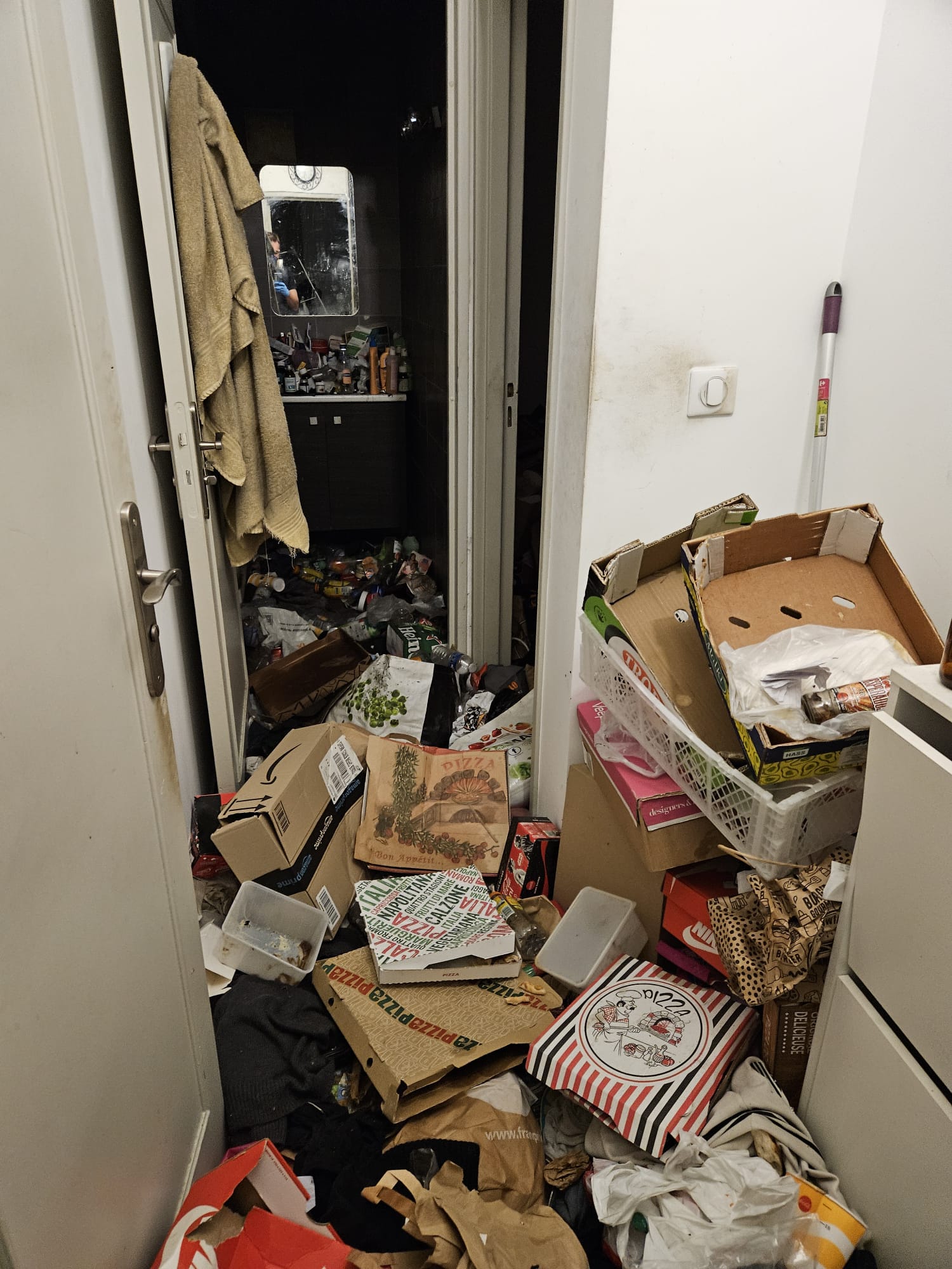 Couloir avant nettoyage extrême : amas de cartons et déchets alimentaires obstruant le passage