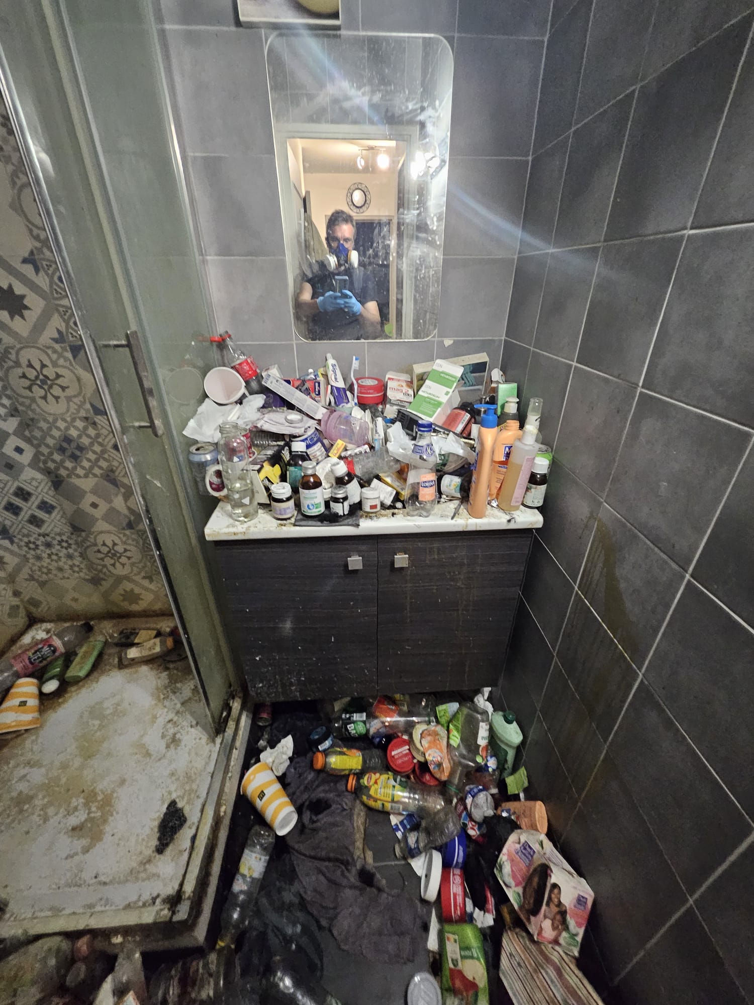 Salle de bains avant nettoyage extrême : accumulation pathologique de médicaments et de déchets, contexte post-mortem